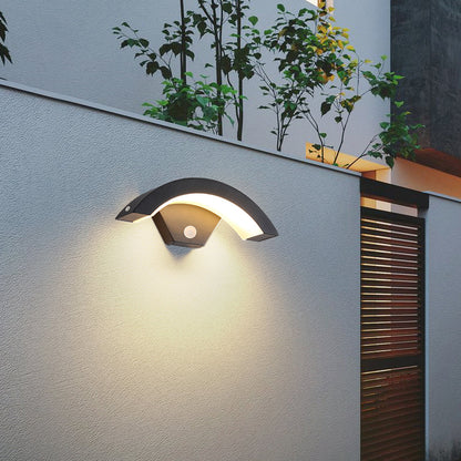Modern black LED curved outdoor induction wall light by Garden Sanctuary mounted on exterior wall, illuminating outdoor space.